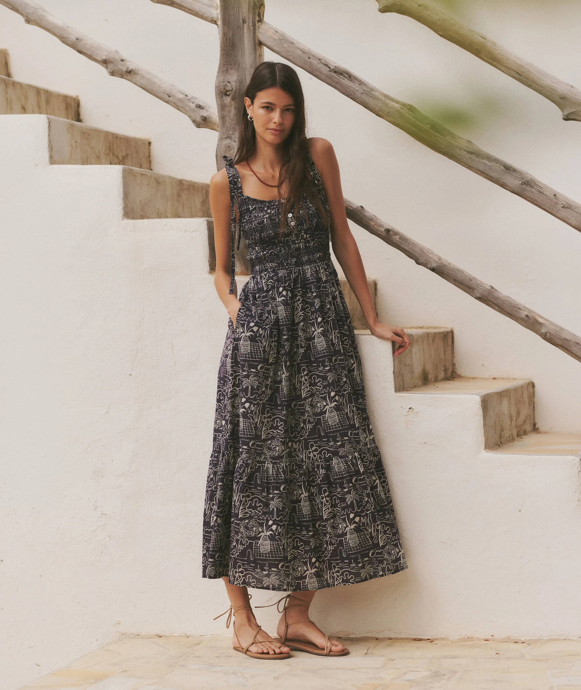 Woman wearing a printed midi dress by a staircase.